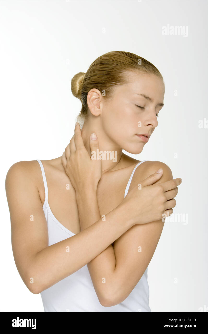 Woman with arms folded across chest, touching neck, eyes closed Stock
