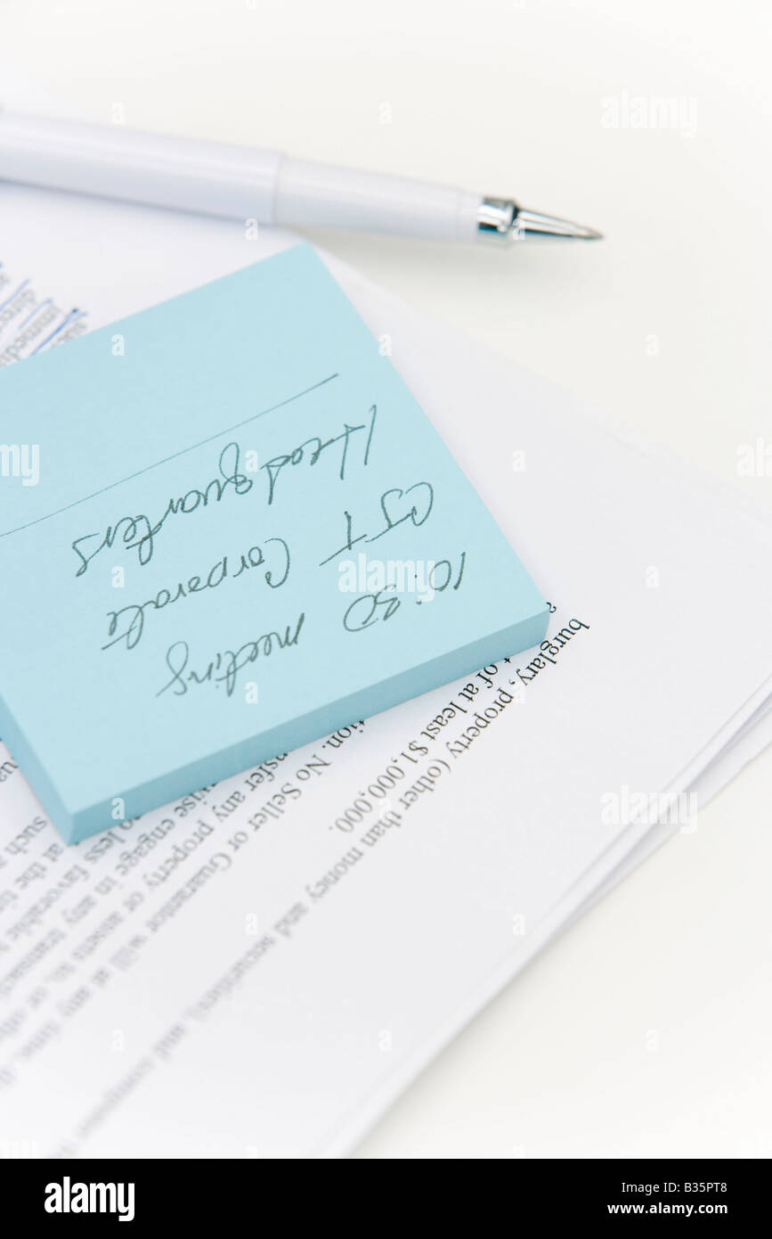 Adhesive note on top of document, pen nearby Stock Photo