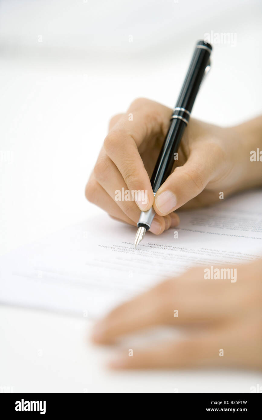Person reviewing document, holding pen, cropped view of hands Stock Photo