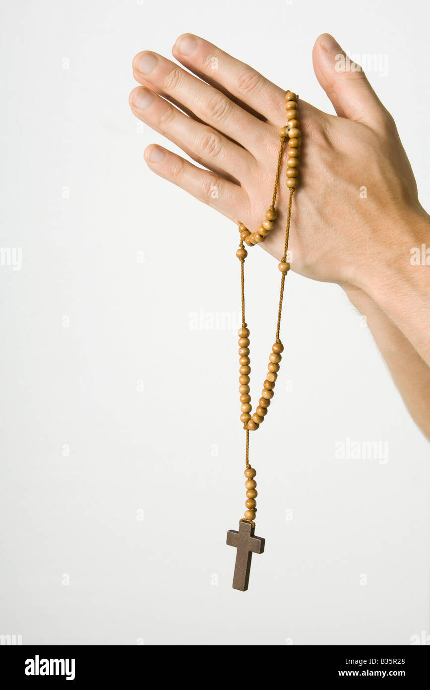 Clasped hands holding rosary with crucifix, cropped view Stock Photo