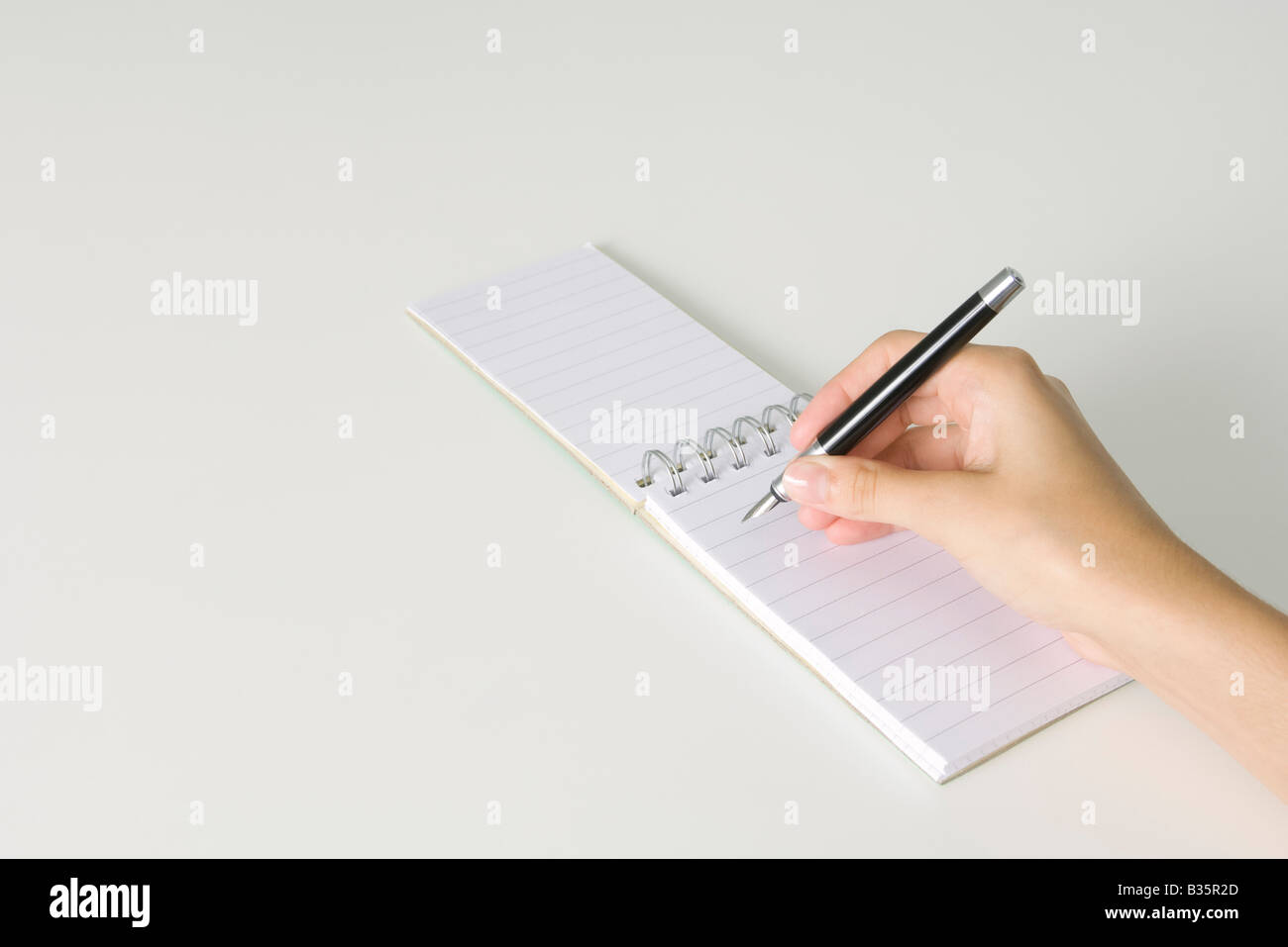 Hand holding pen, poised to write in notepad flipped open, cropped view Stock Photo