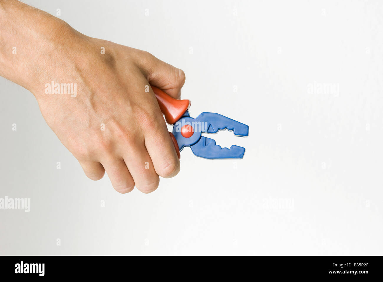 Hand holding toy pliers, cropped view Stock Photo - Alamy