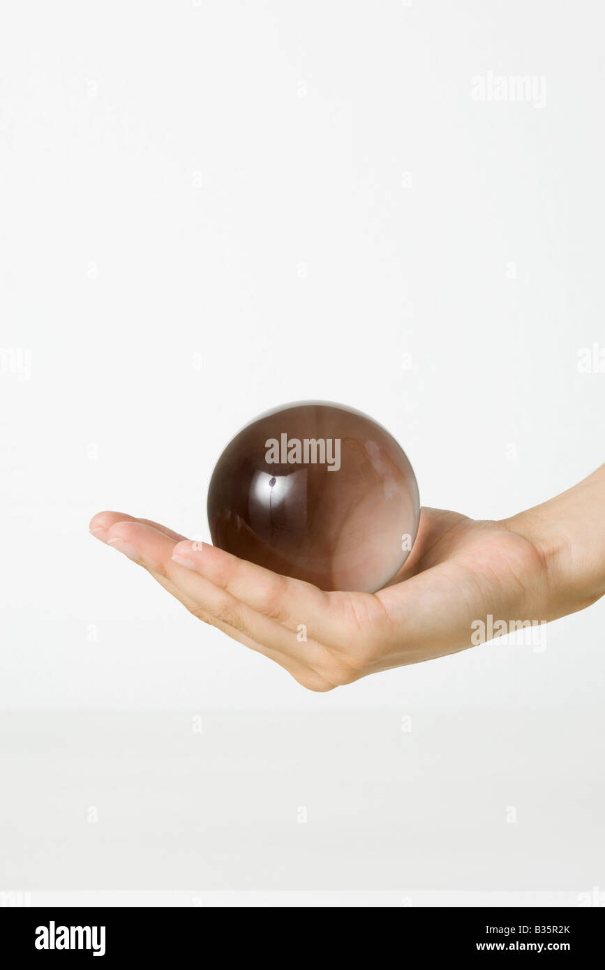 Cupped hand holding crystal ball, cropped view Stock Photo