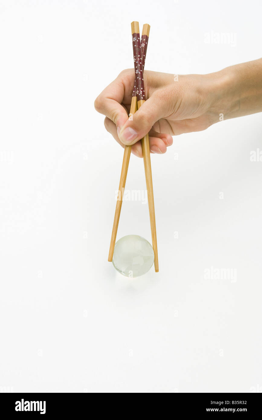 Hands using chopsticks to hold transparent globe, cropped view Stock Photo