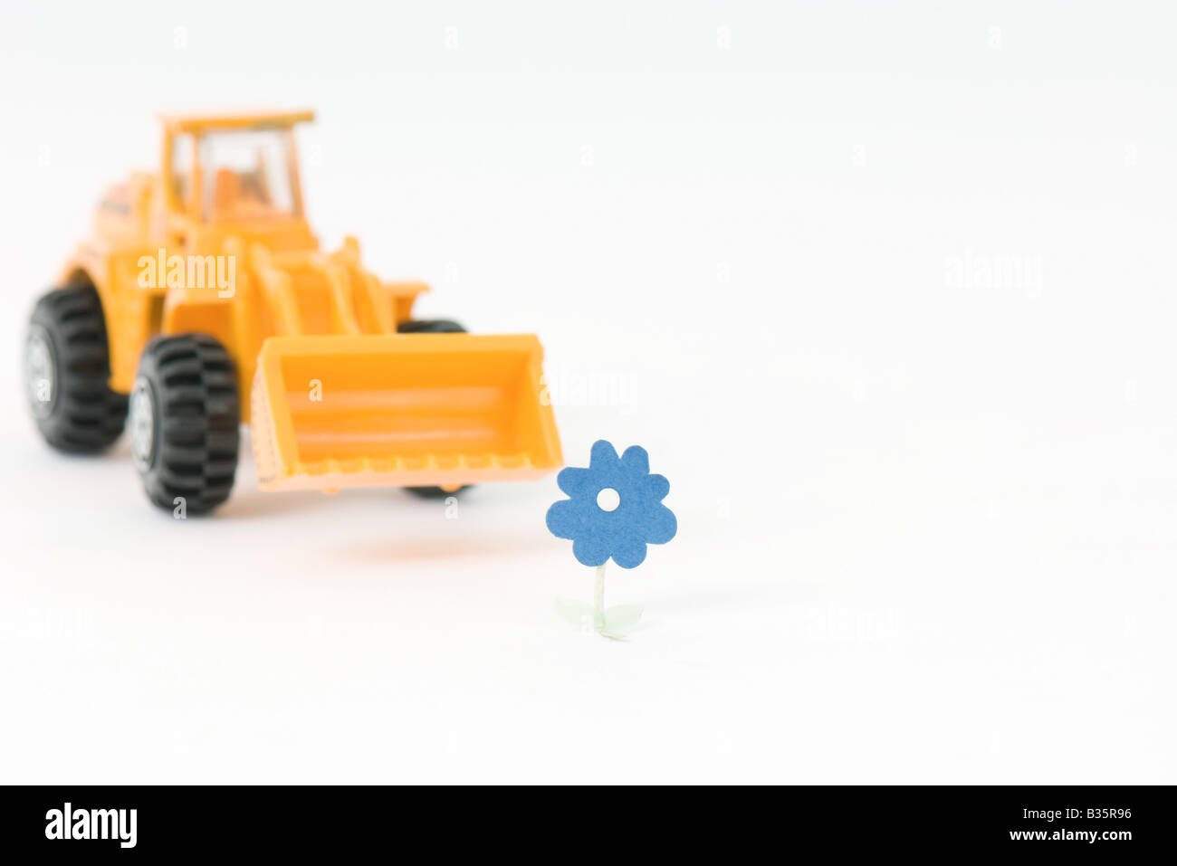 Toy bulldozer approaching flower Stock Photo