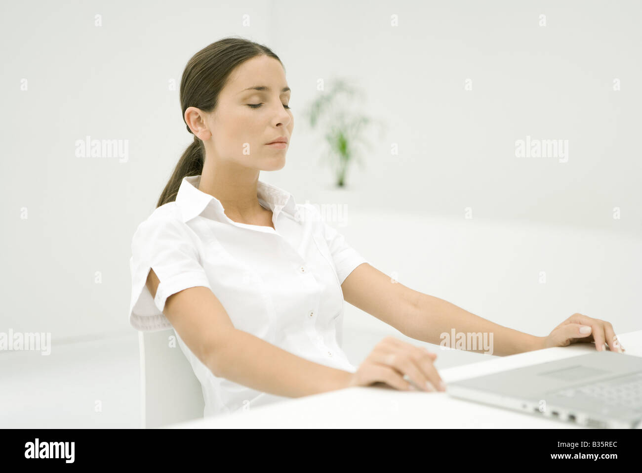 Woman sitting with laptop, eyes closed Stock Photo - Alamy