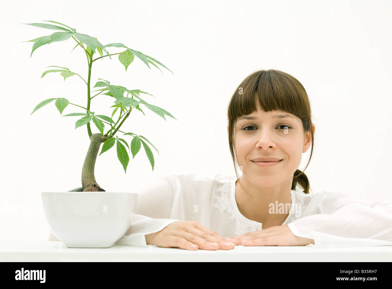 Woman sitting with potted plant, smiling at camera Stock Photo - Alamy