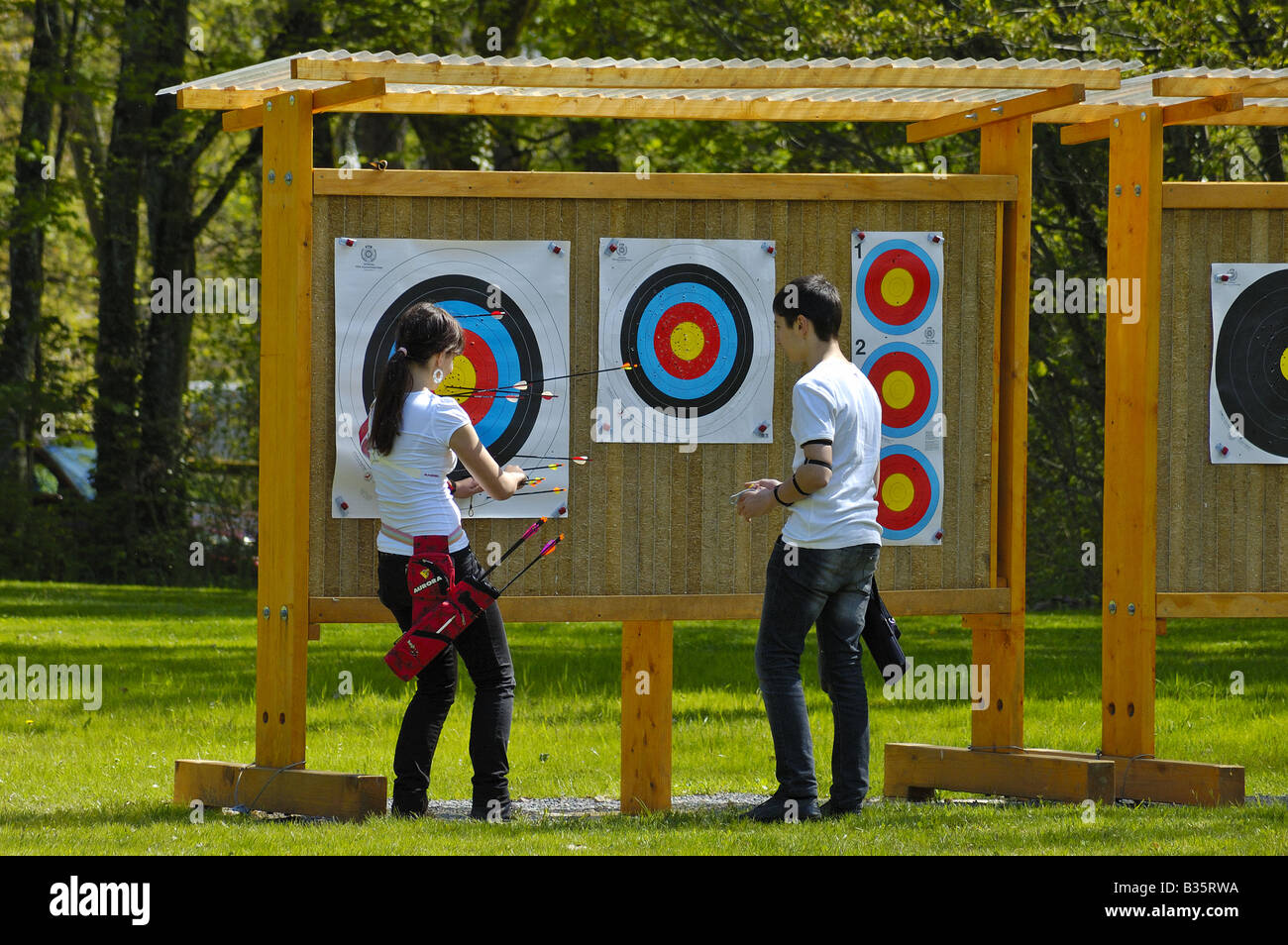 Two archers pull their arrows out of the target, checking their score. Stock Photo