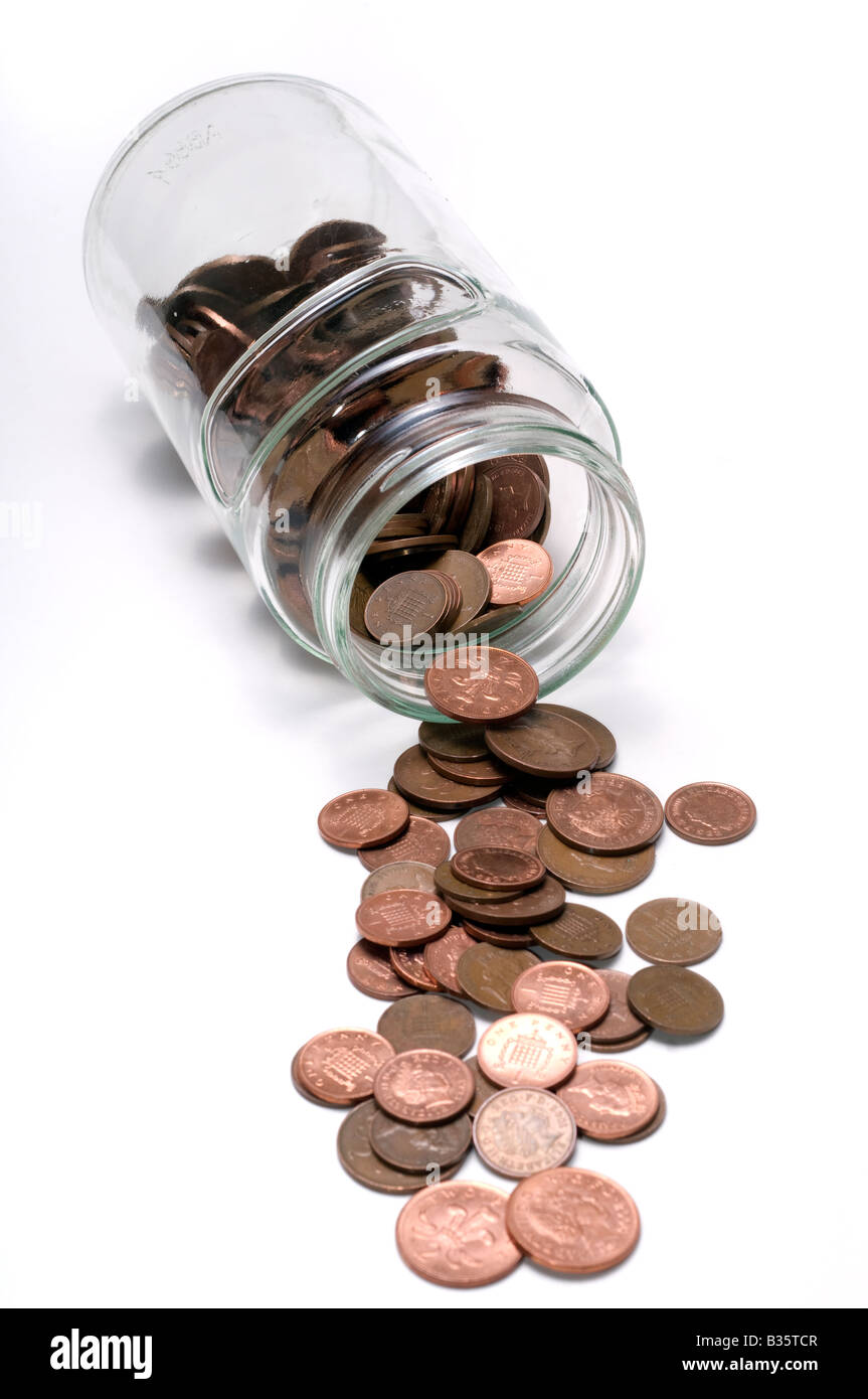 Glass jar spilling out copper coins Stock Photo