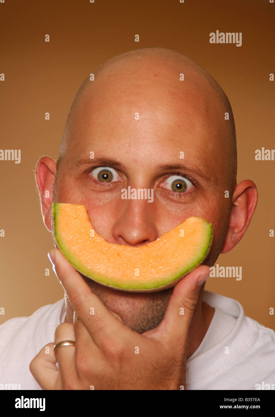 Portrait of a mid adult man holding a slice of cantaloupe Stock Photo