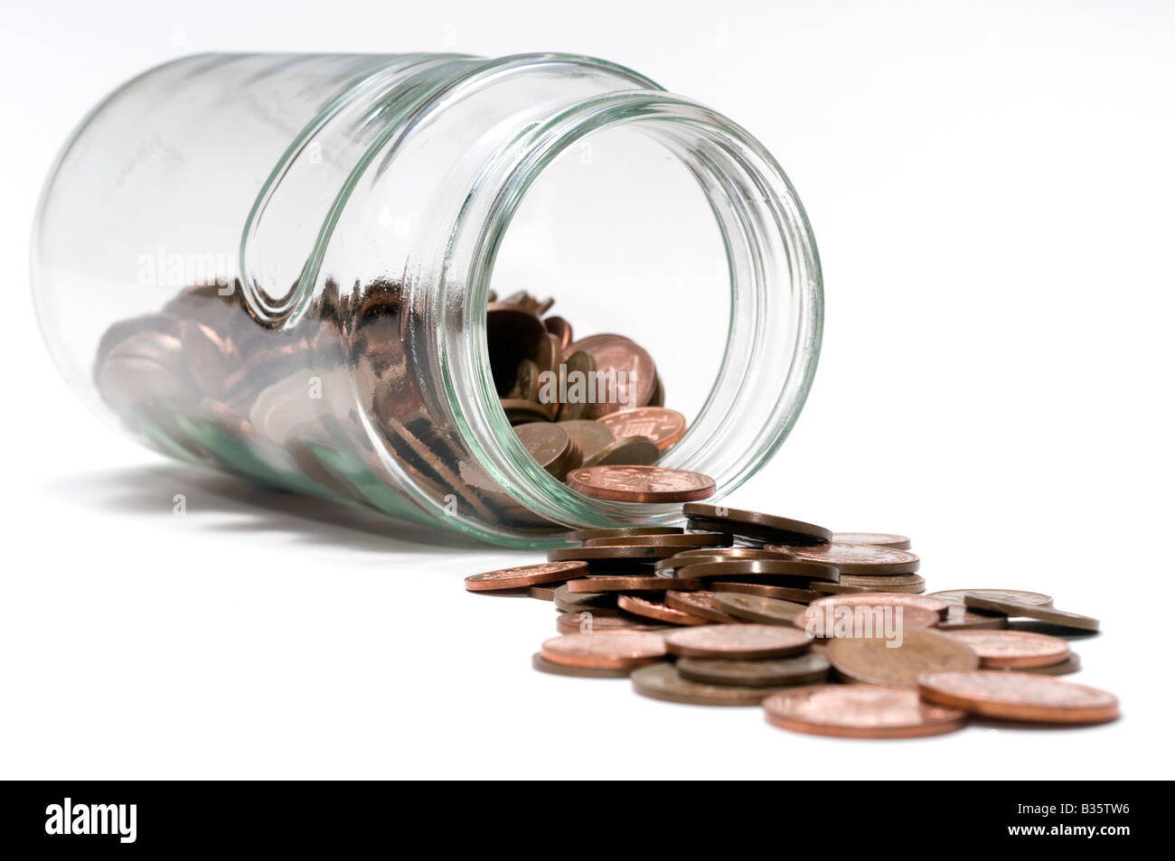 Glass jar spilling out copper coins Stock Photo
