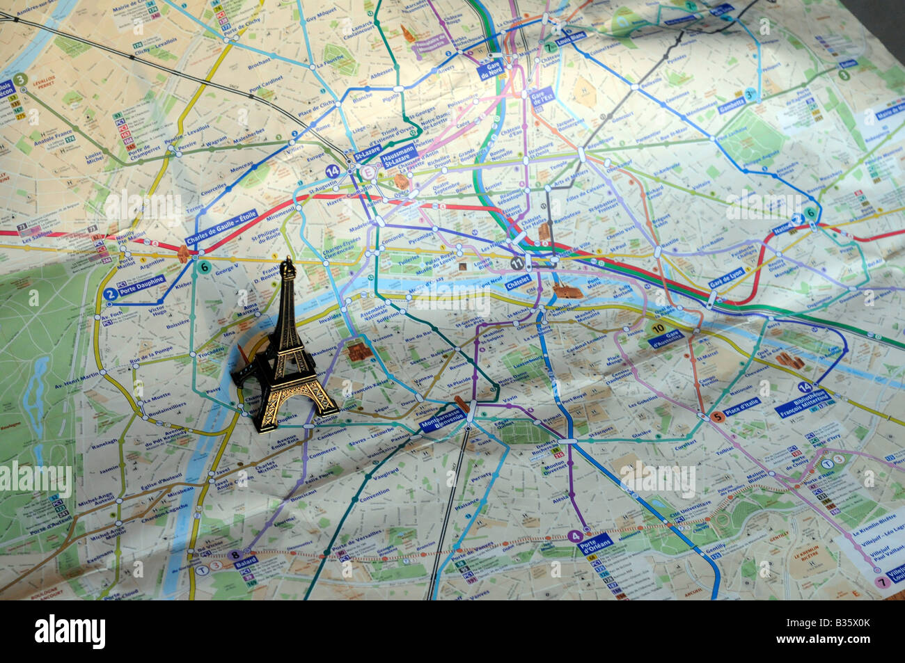 A small-scale model of the eiffel tower standing on a map of Paris, France Stock Photo