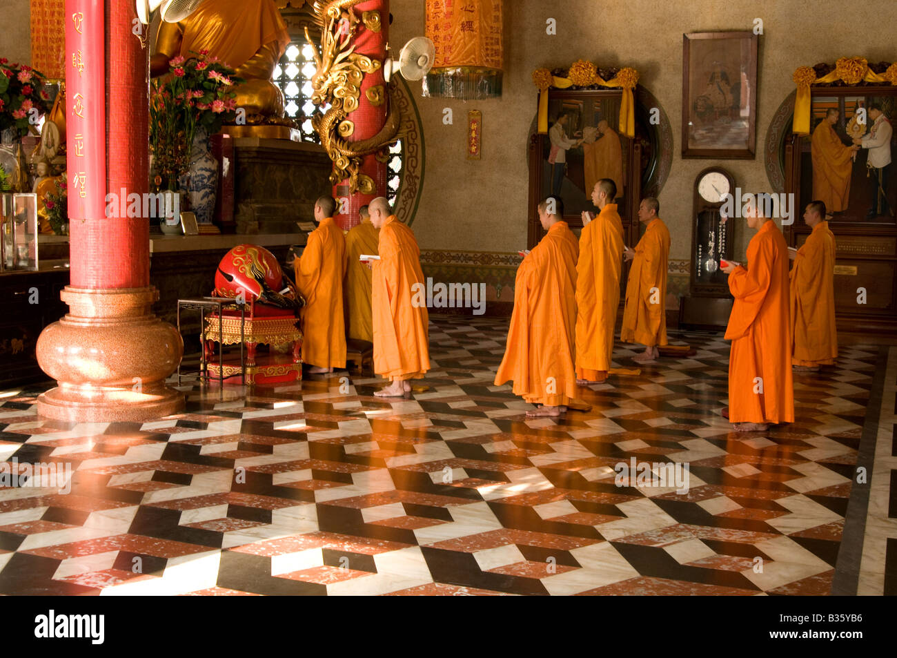 Large group of Buddhist monks stand at prayer in Wat Bhoman temple