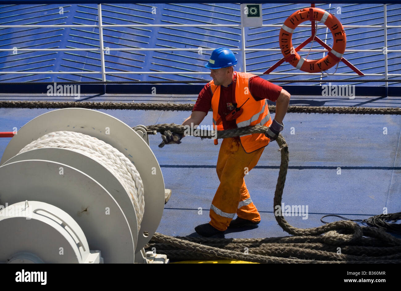 Man pulling a rope on a ship deck leaving the port, Mallorca Island, Spain Stock Photo