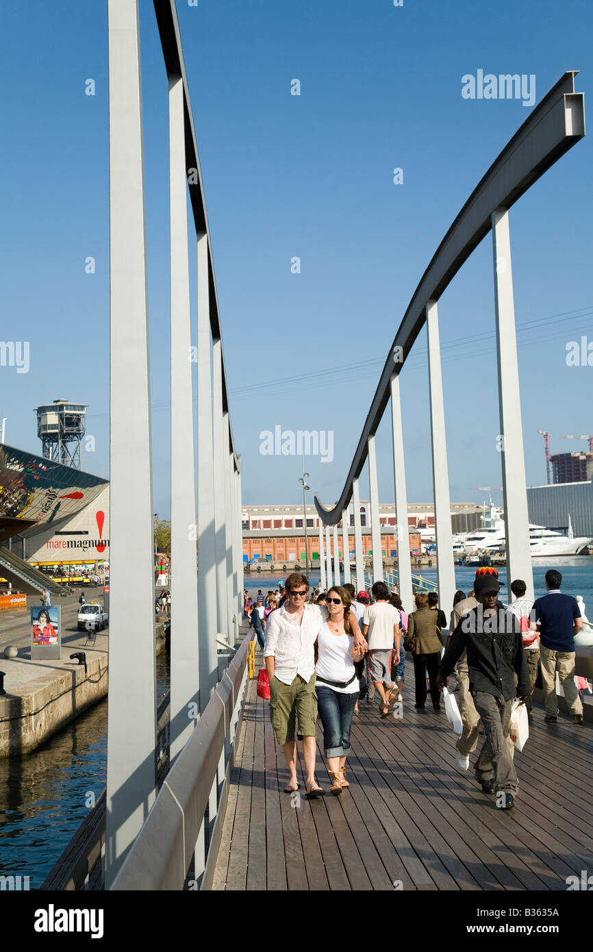 SPAIN Barcelona Young couple walk on wooden pedestrian bridge to Maremagnum mall at Marina Port Vell Stock Photo