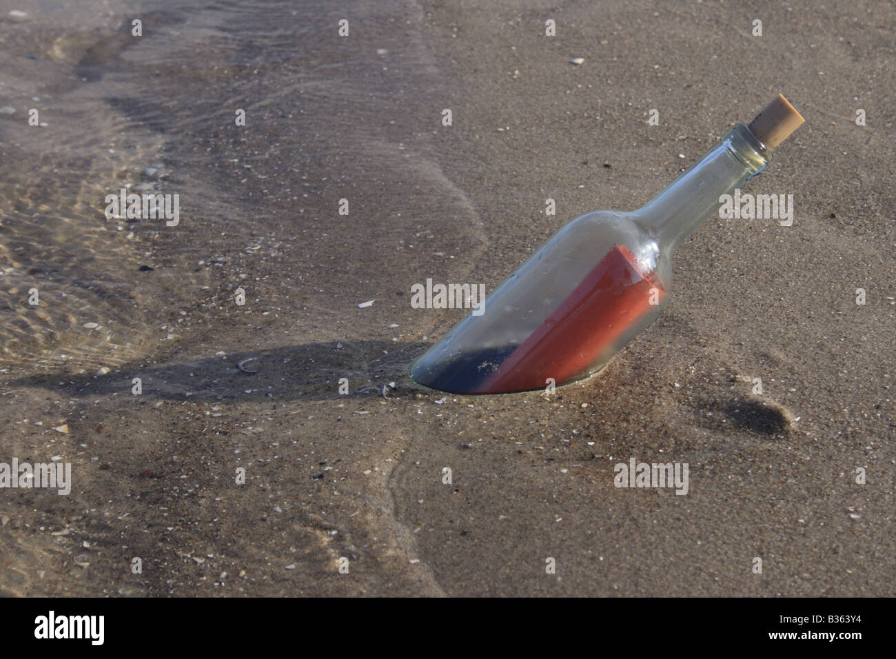 red letter as message in a bottle on sandy beach. Photo by Willy Matheisl Stock Photo