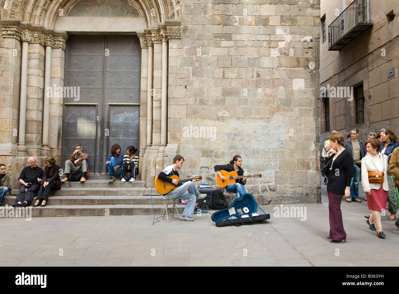 SPAIN Barcelona Two young adult men play acoustic guitar in plaza with open guitar case selling CDs of music people listen Stock Photo