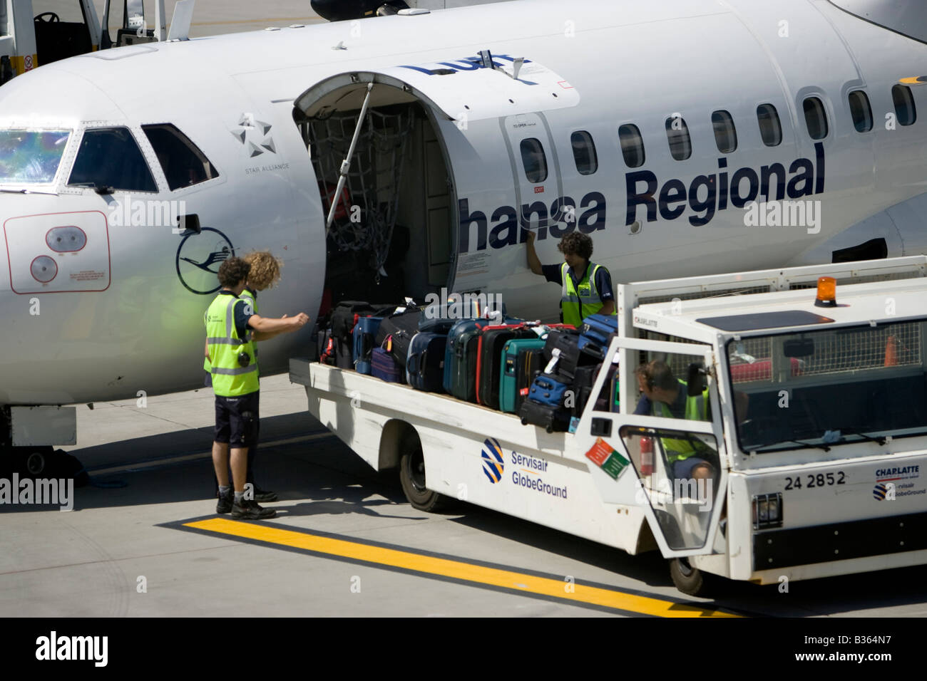 Lufthansa Regional Baggage handler moving luggage at airport air side British Airport Jersey Channel Islands Stock Photo