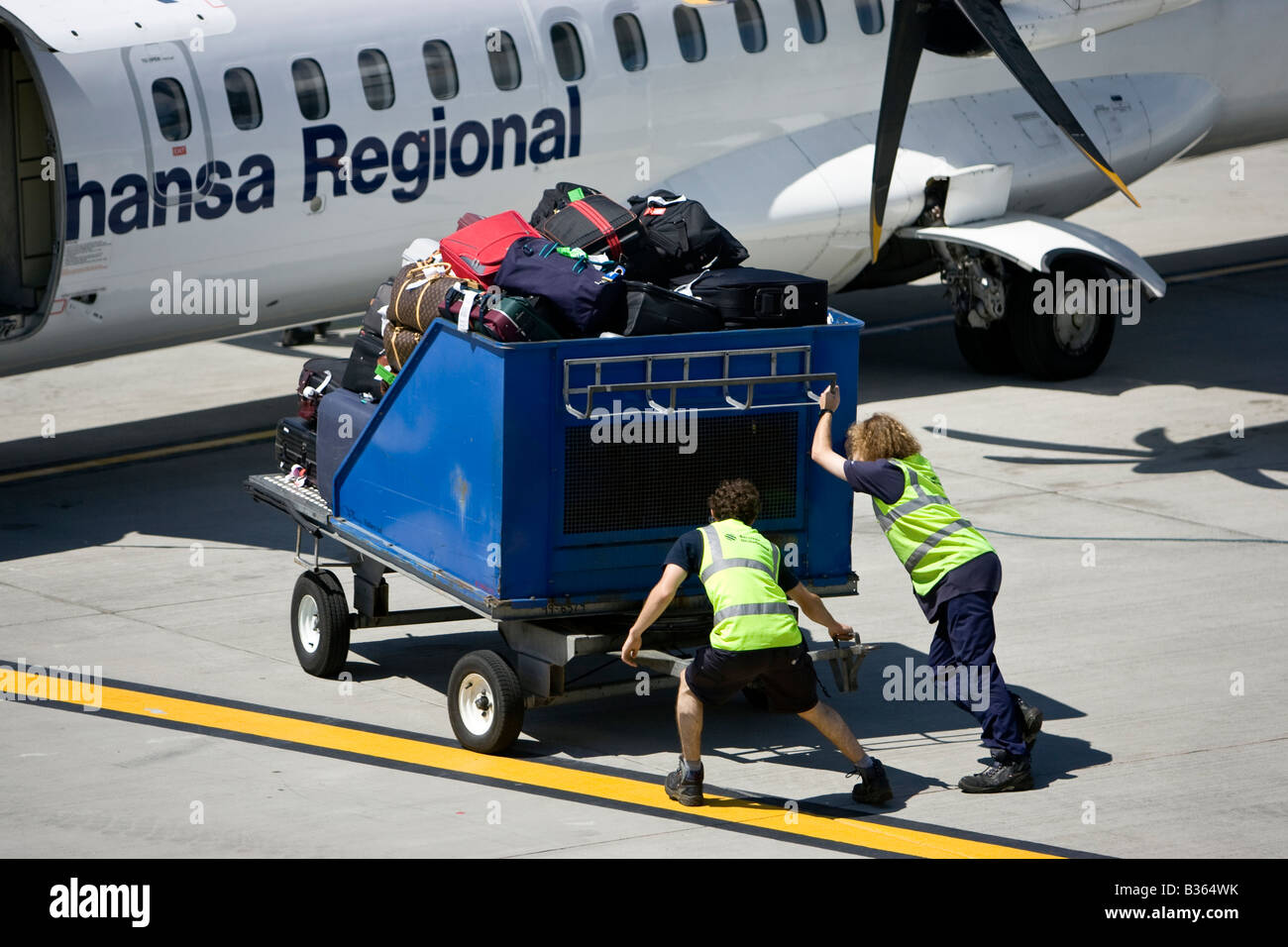 Lufthansa Regional Baggage handler moving luggage at airport air side British Airport Jersey Channel Islands Lufthansa Regional Stock Photo