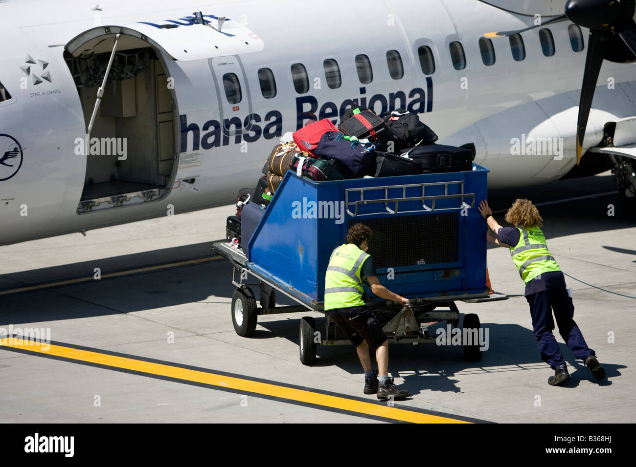 Lufthansa Regional Baggage handler moving luggage at airport air side British Airport Jersey Channel Islands Stock Photo