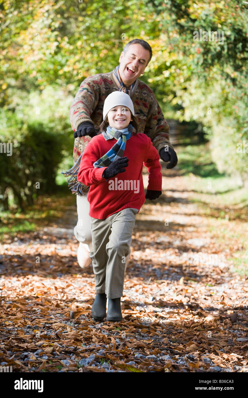 Grandfather and grandson running outdoors in park and smiling Stock Photo