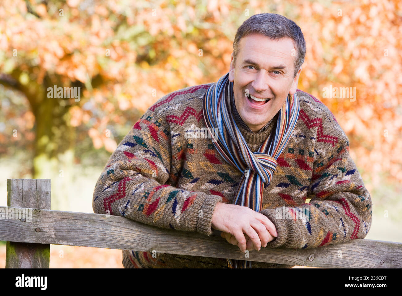 Man outdoors at park leaning on fence smiling (selective focus) Stock Photo