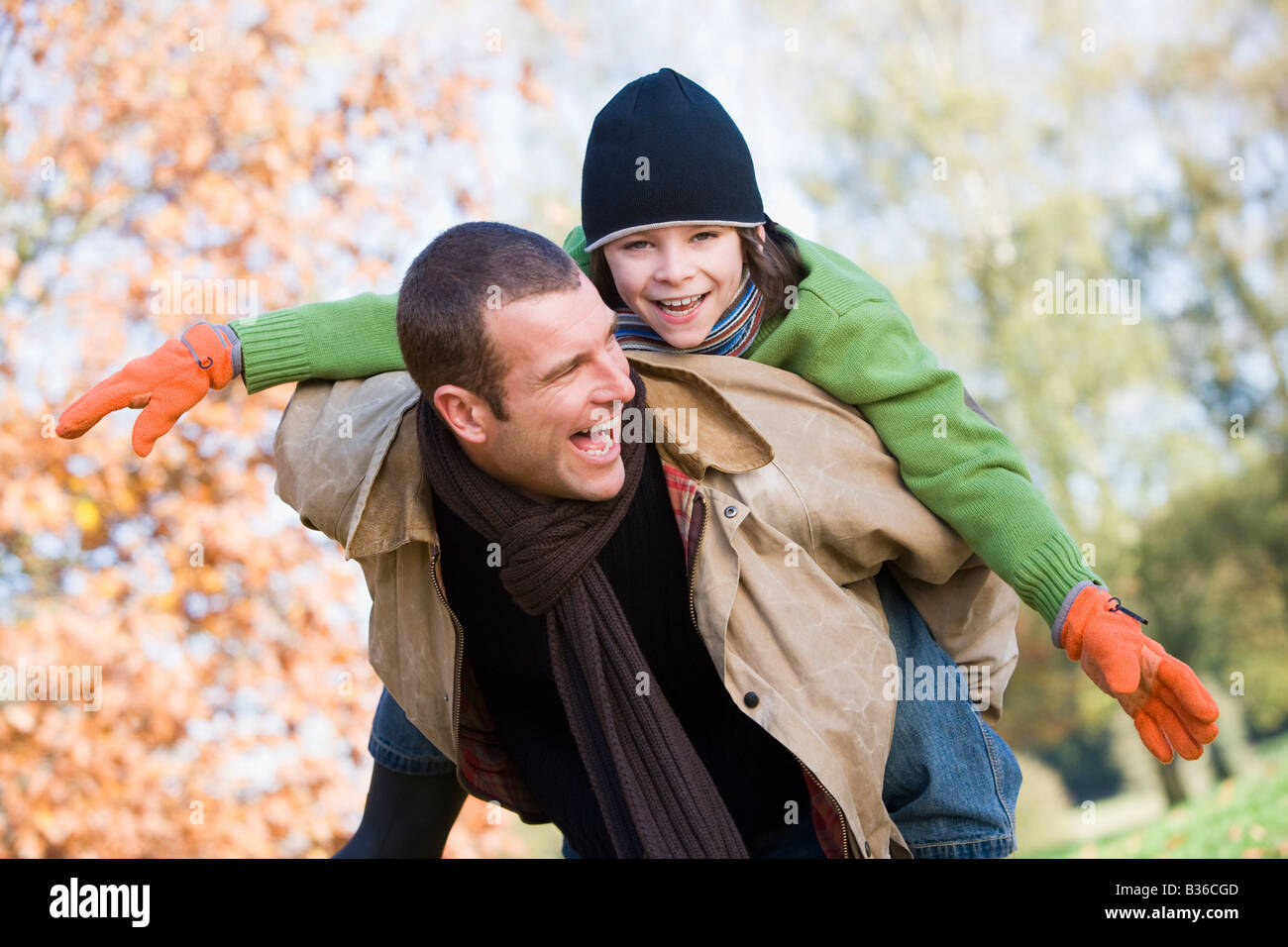 Father outdoors piggybacking son and smiling (selective focus) Stock Photo