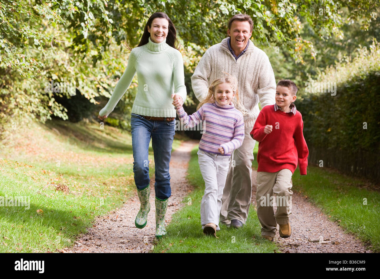 семья из 4 человек гуляет по парку. гулять по парку. прогулка по парку. всей семьей идут гулять ночью вдоль дорожек. веселая семья в лесу.