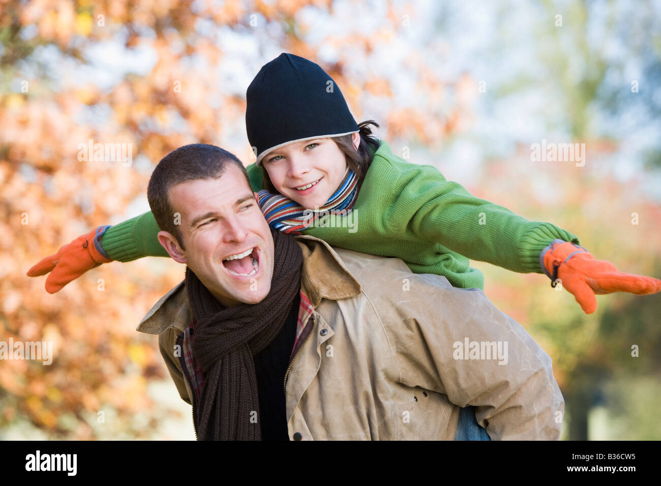 Father piggybacking son outdoors at park and smiling (selective focus) Stock Photo