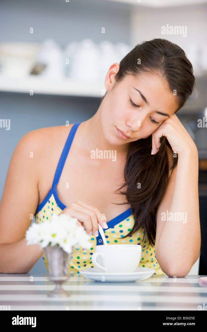 Young woman sitting at a table drinking tea Stock Photo