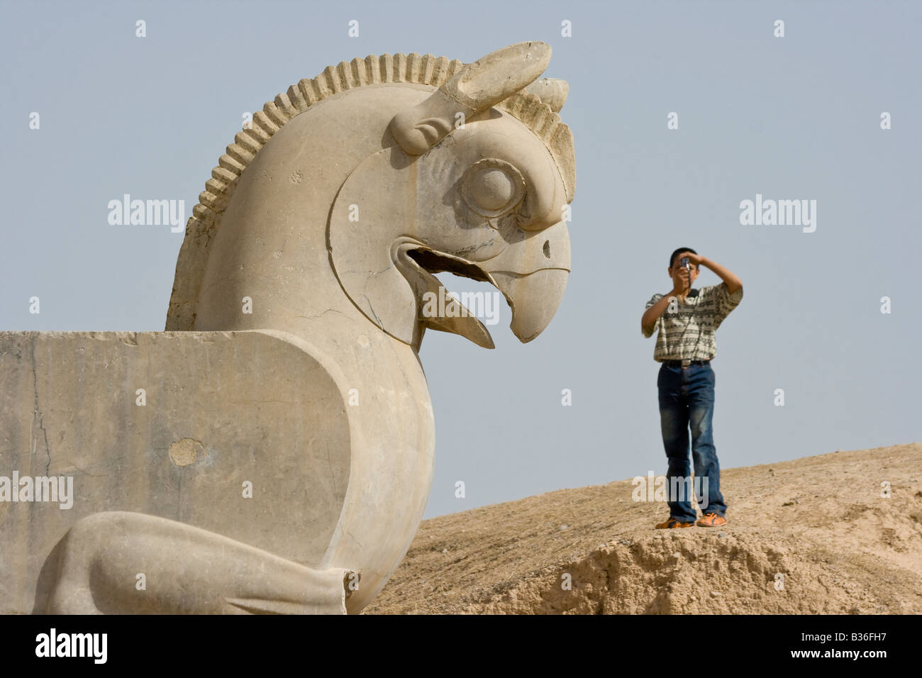 Iranian boy taking a picture of the Statue of a Homa at the Ruins of Persepolis Stock Photo