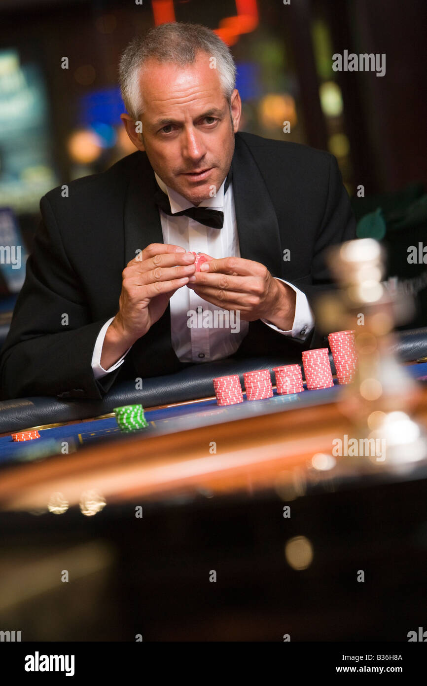 Man in casino playing roulette holding chips (selective focus) Stock Photo