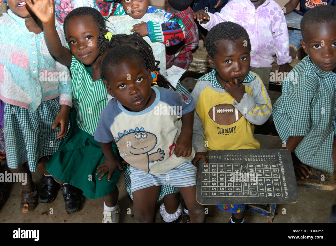 Pre school children holding an alphabet table in a simple day care centre in Akropong Akwapim, Eastern Region, Ghana Stock Photo