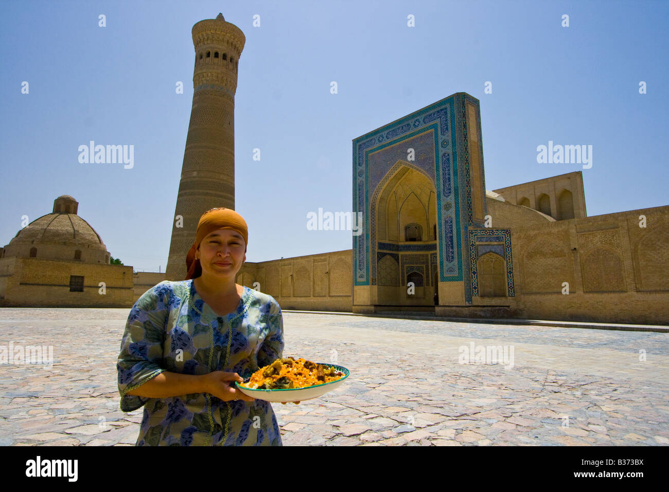 Woman with Plov in front of the Kalon Mosque and Minaret in Bukhara Uzbekistan Stock Photo