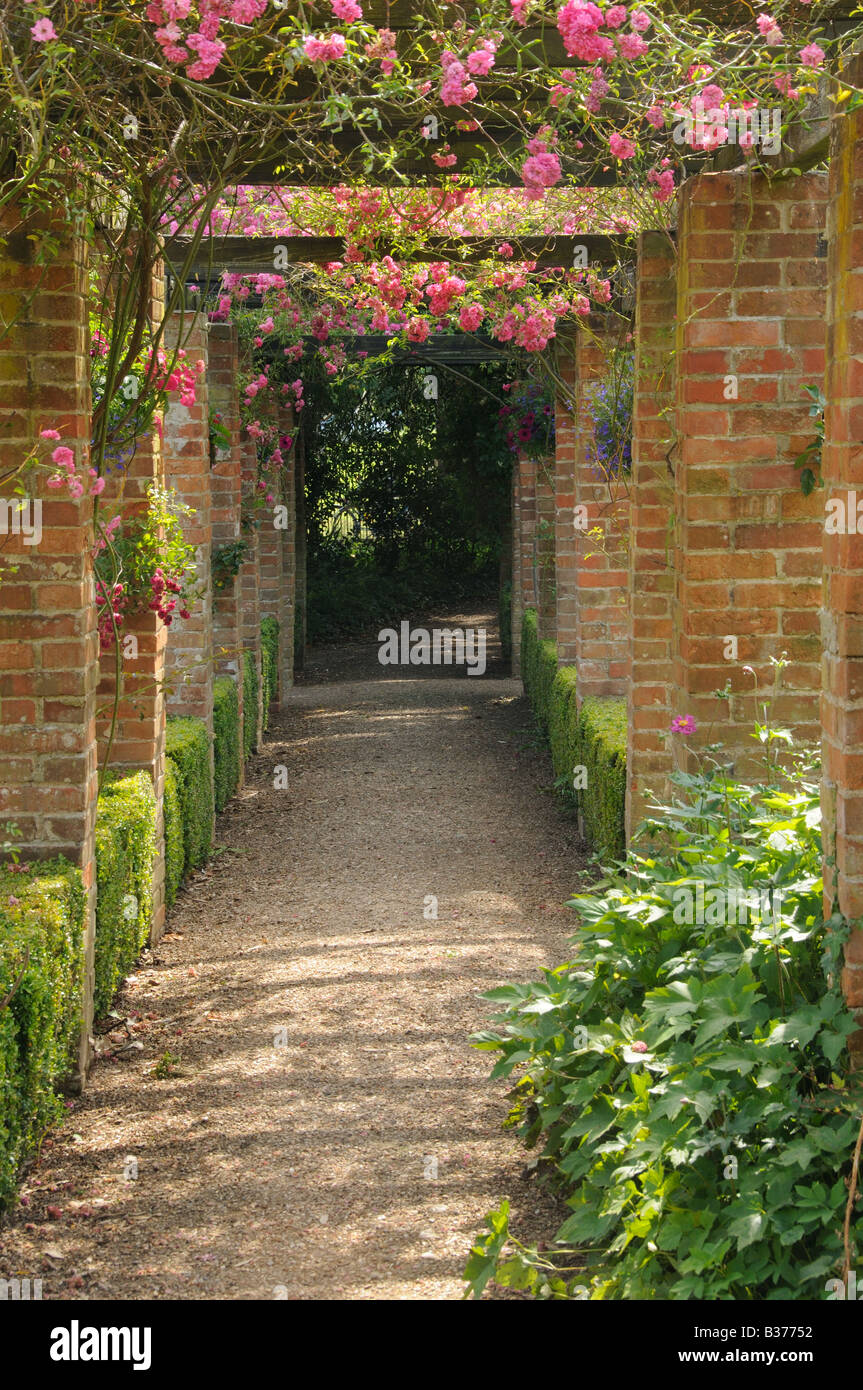 Large brick pergola with roses in country house garden UK July Stock Photo