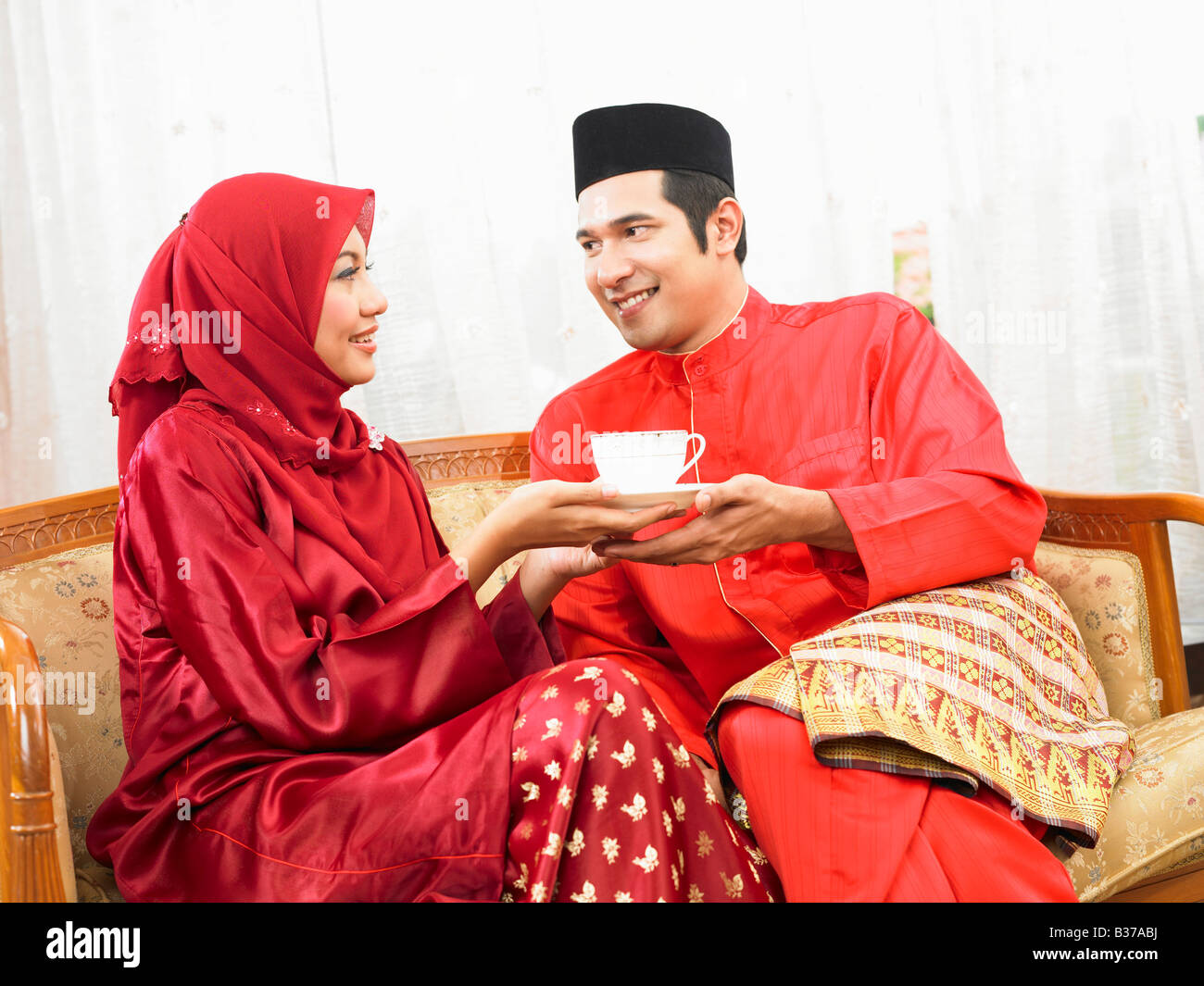 Malay couple having coffee, sitting on sofa Stock Photo
