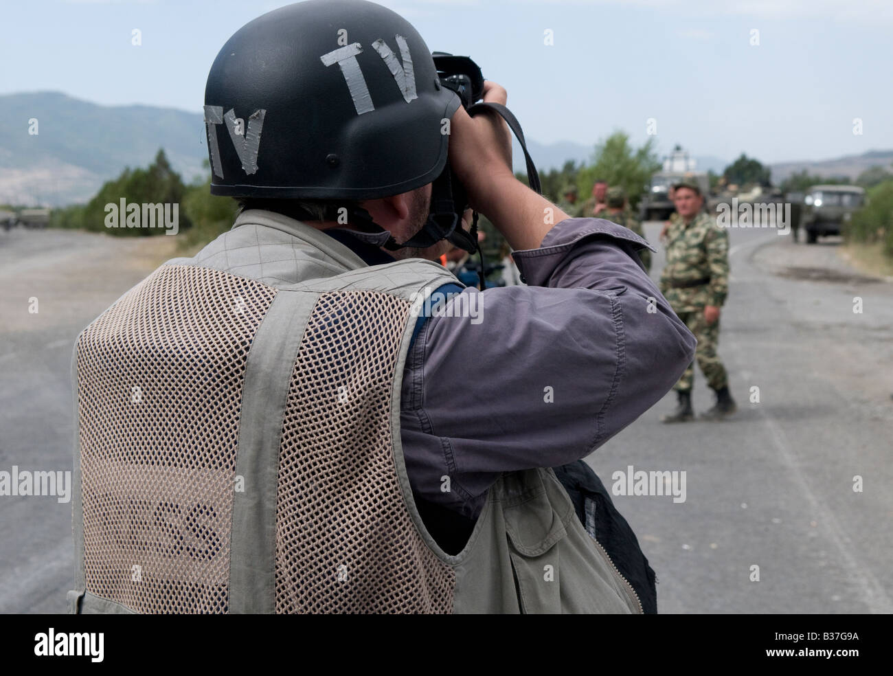 A photojournalist wearing vest marked 'Press' and helmet marked 'TV' photographing Russian troops during the Russo-Georgian War August 2008 Stock Photo