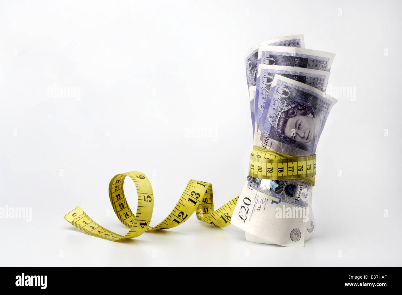 £20 notes being squeezed by a tape measure Stock Photo