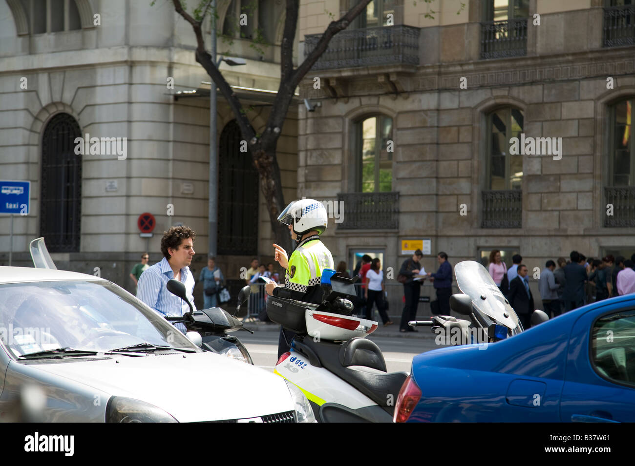 SPAIN Barcelona Motorcycle policeman talk and gesture to stopped young adult male on motorcycle in center of street Stock Photo