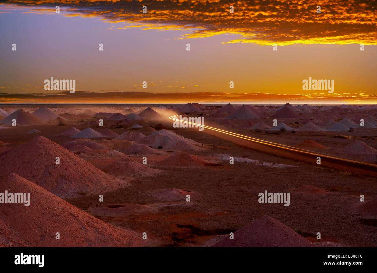 headlights driving through scene  Outback panorama of opal mines at sunset, Coober Pedy South Australia Stock Photo