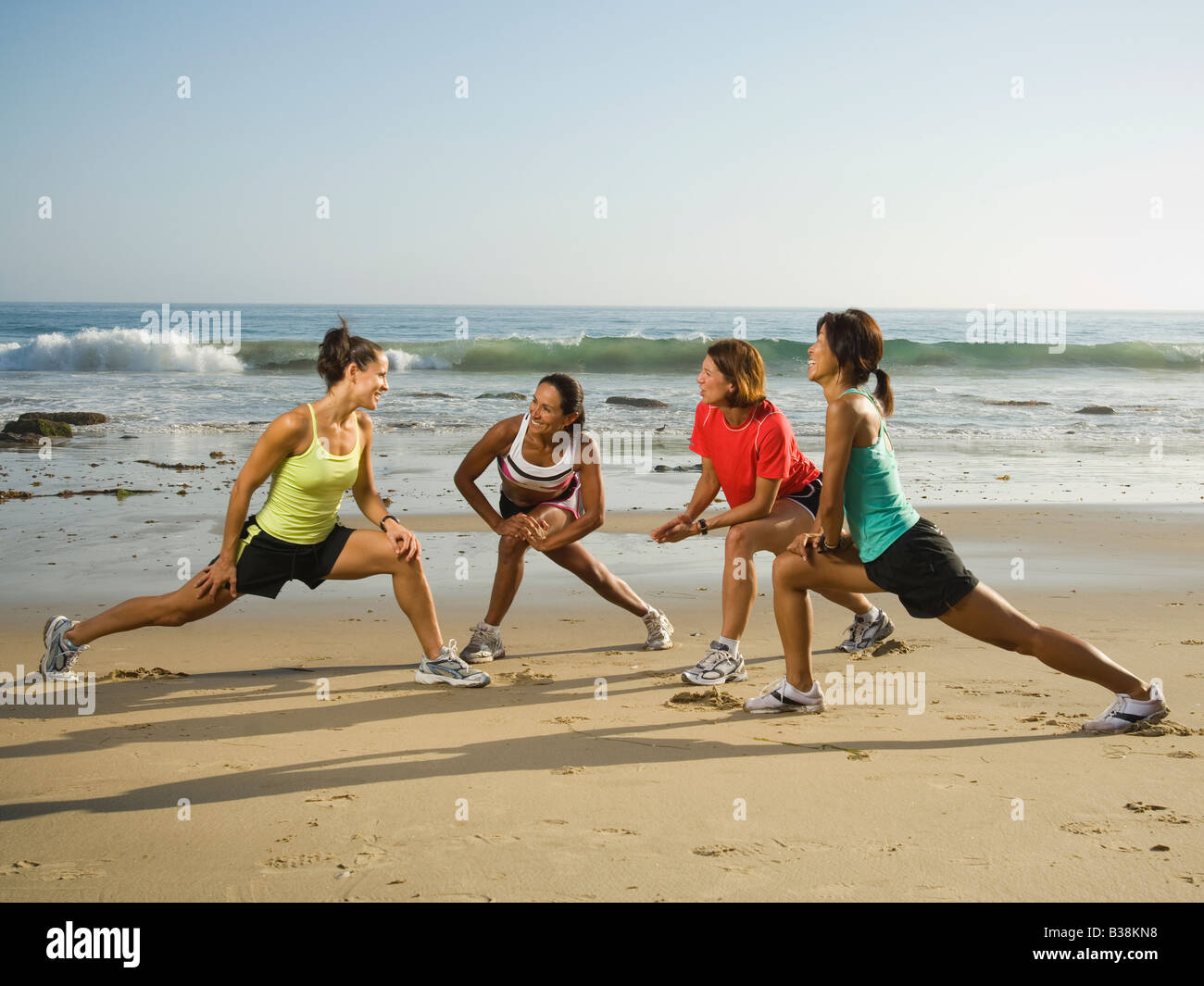 Multi-ethnic runners stretching at beach Stock Photo - Alamy