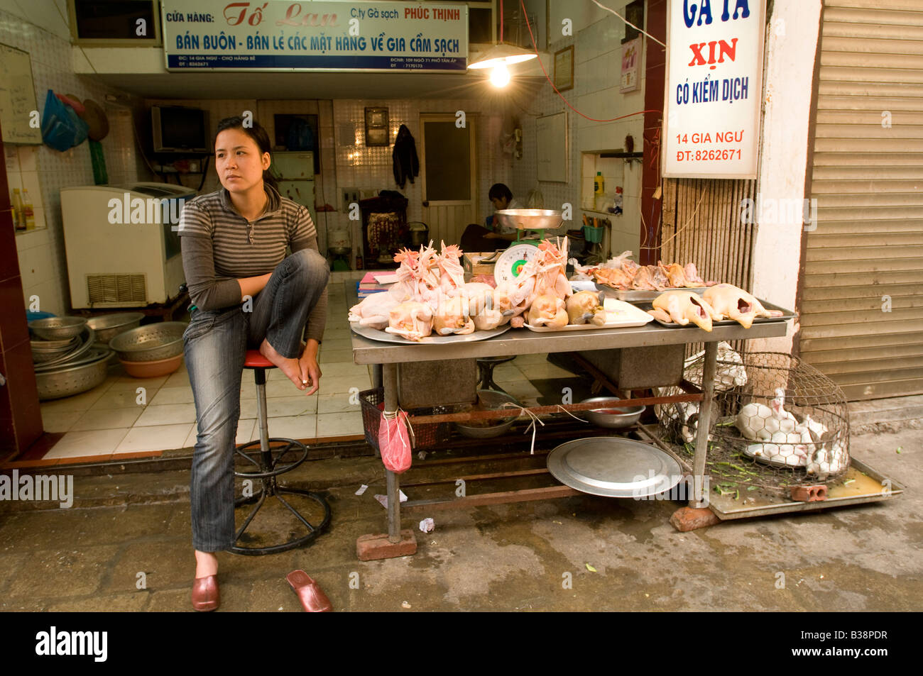 A Vietnamese woman looking bored on her chicken stall in the Old Quarter of Hanoi Vietnam Stock Photo