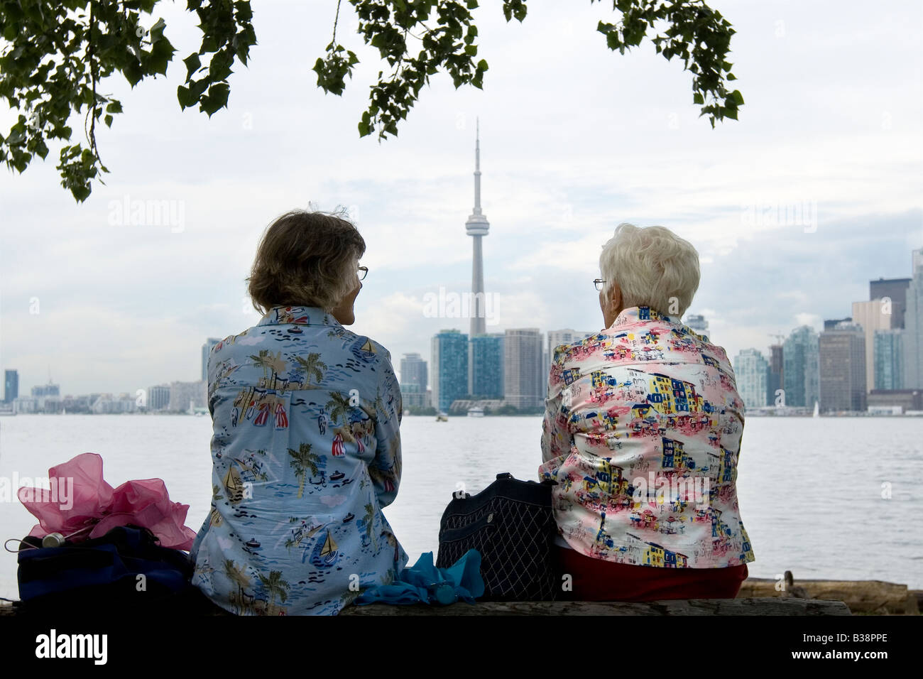 Two ladies sitting opposite the CN tower in Toronto Canada Stock Photo