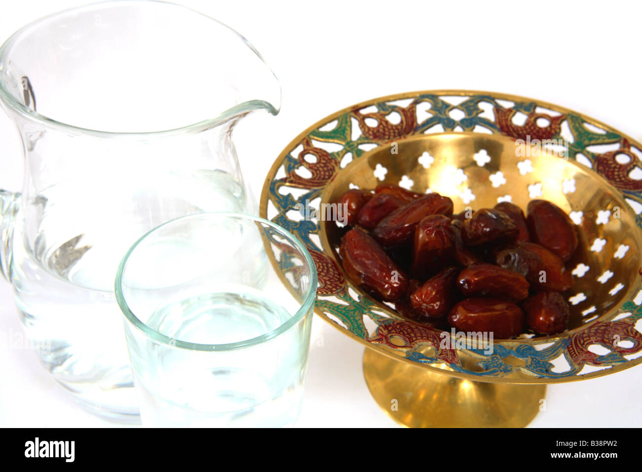 A bowl of dates and a jug and glass of water Stock Photo