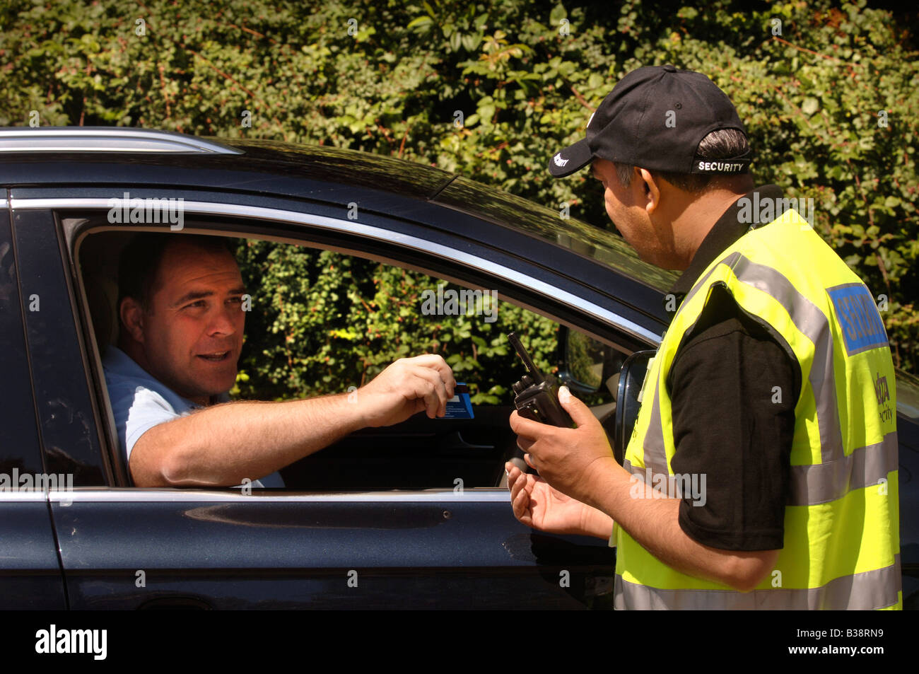 A SECURITY GUARD CHECKS AN IDENTIFICATION BADGE AT THE GATEHOUSE OF SECURE PREMISES UK Stock A SECURITY GUARD CHECKS AN IDENTIFICATION BADGE AT THE GATEHOUSE OF SECURE PREMISES UK Stock
