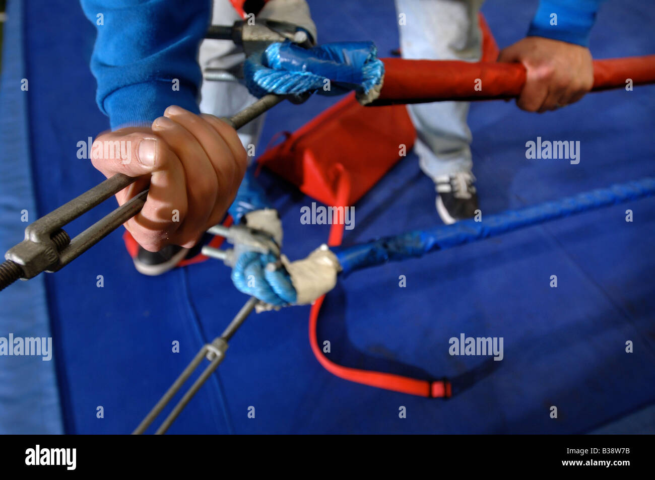 A MAIN TIGHTENS THE TURNBUCKLES ON A BOXING RING BUILT FOR THE BOXER