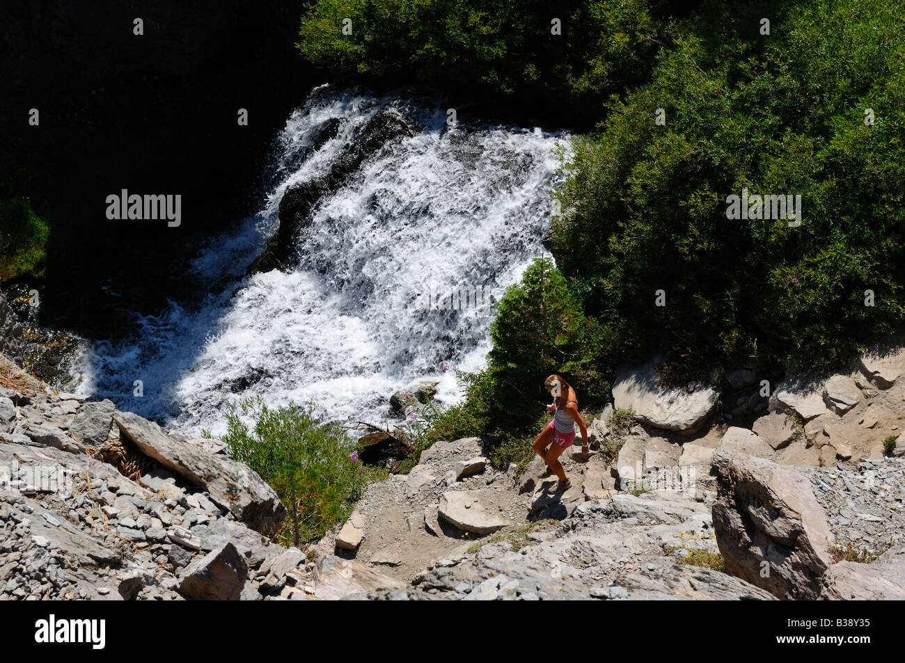 A hiker walking by a cascade along a mountain trail. Lassen Volcanic National Park, California, USA. Stock Photo