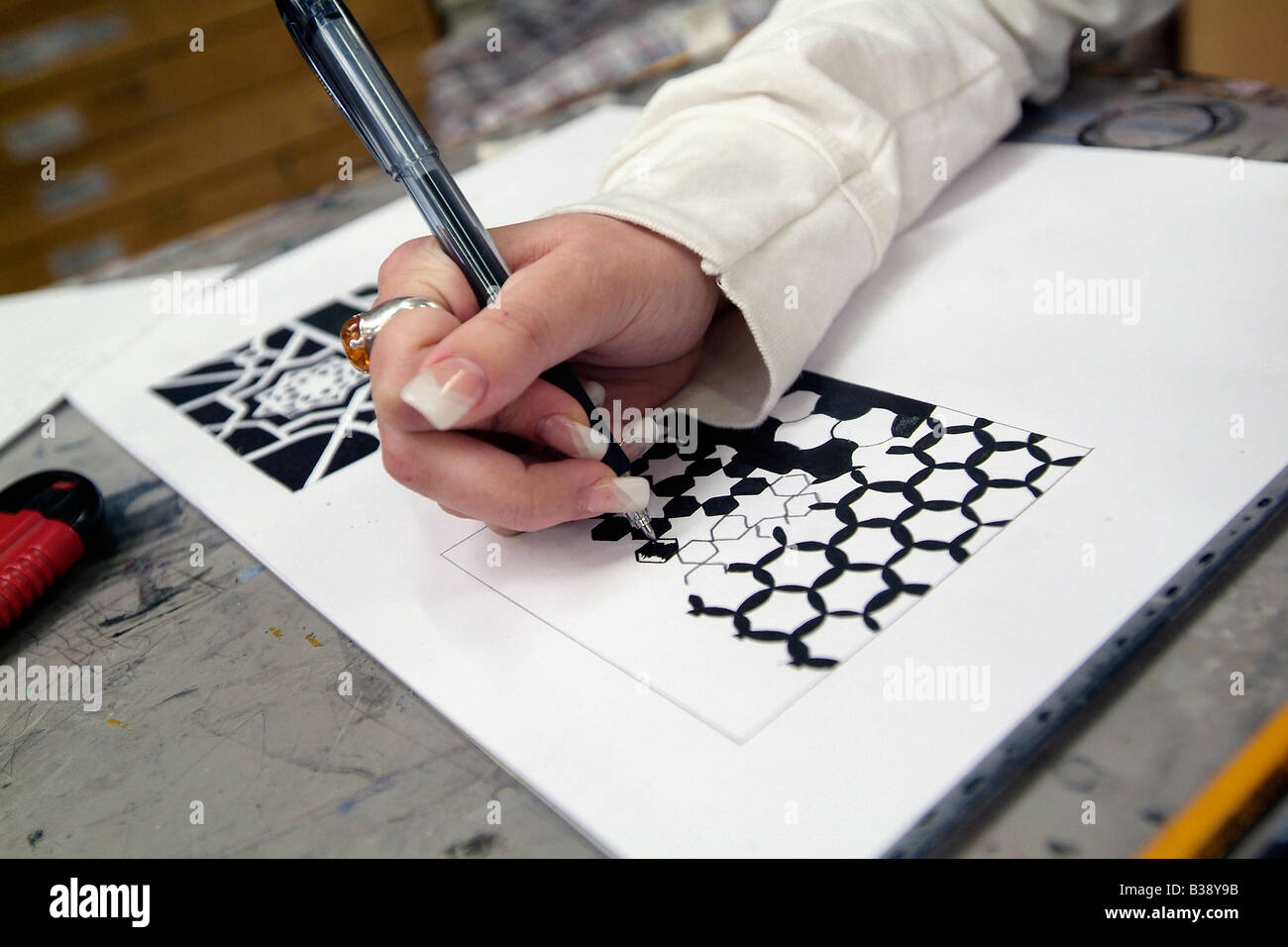 Close-up of female art student's hand drawing a symmetrical design in black ink Stock Photo