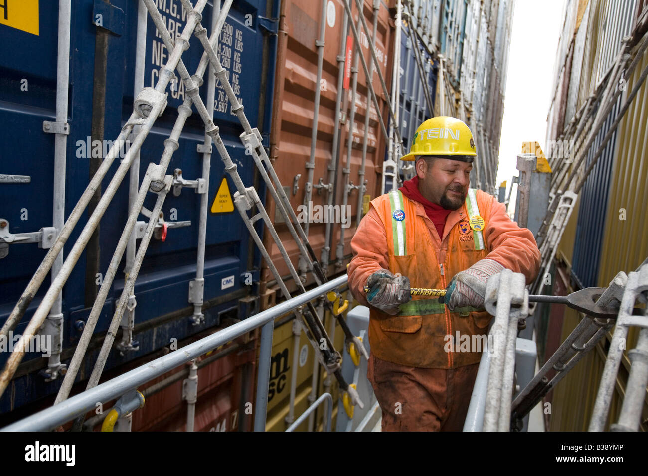 Longshoreman secures shipping containers on ship in the Port of Oakland Stock Photo