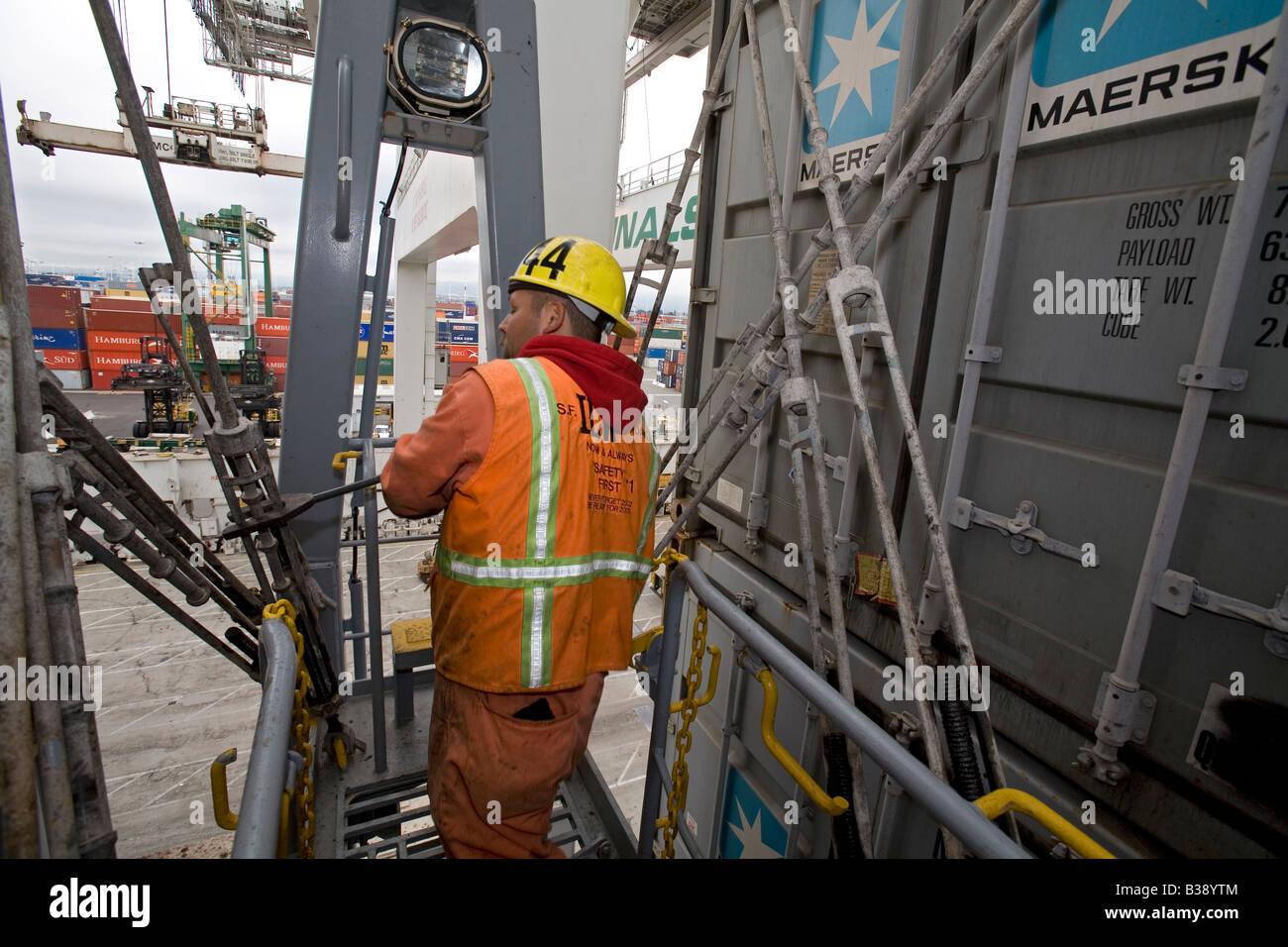 Longshoreman secures shipping containers on ship in the Port of Oakland Stock Photo